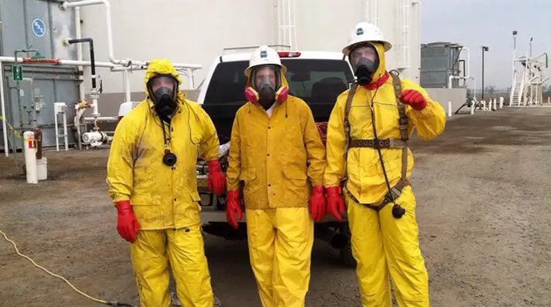 Alliance crew in chemical suits and respirators at an industrial tank site